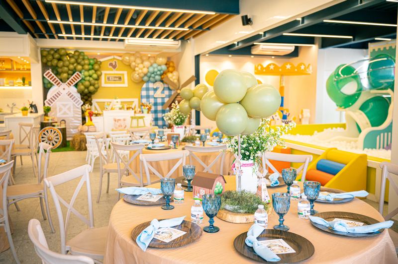 El salón privado de PKB decorado para una fiesta de granja, con mesas redondas y los toboganes al fondo